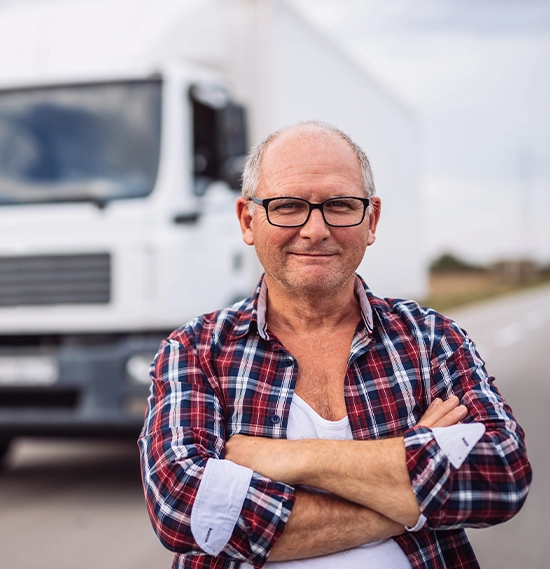 Truck driver with crossed arms standing in front of the truck