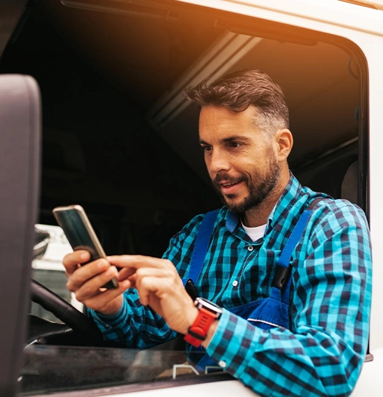 Truck driver holding a phone inside his truck