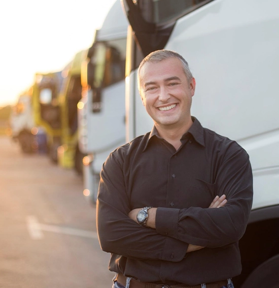 A commercial truck owner with arms crossed, with vehicles in the background