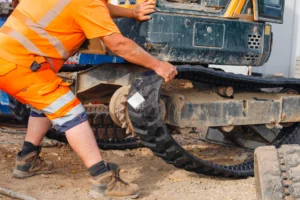 Construction machinery excavator repaired by mechanic, paid for with equipment and machinery finance, and new rubber track being fitted to it on construction site